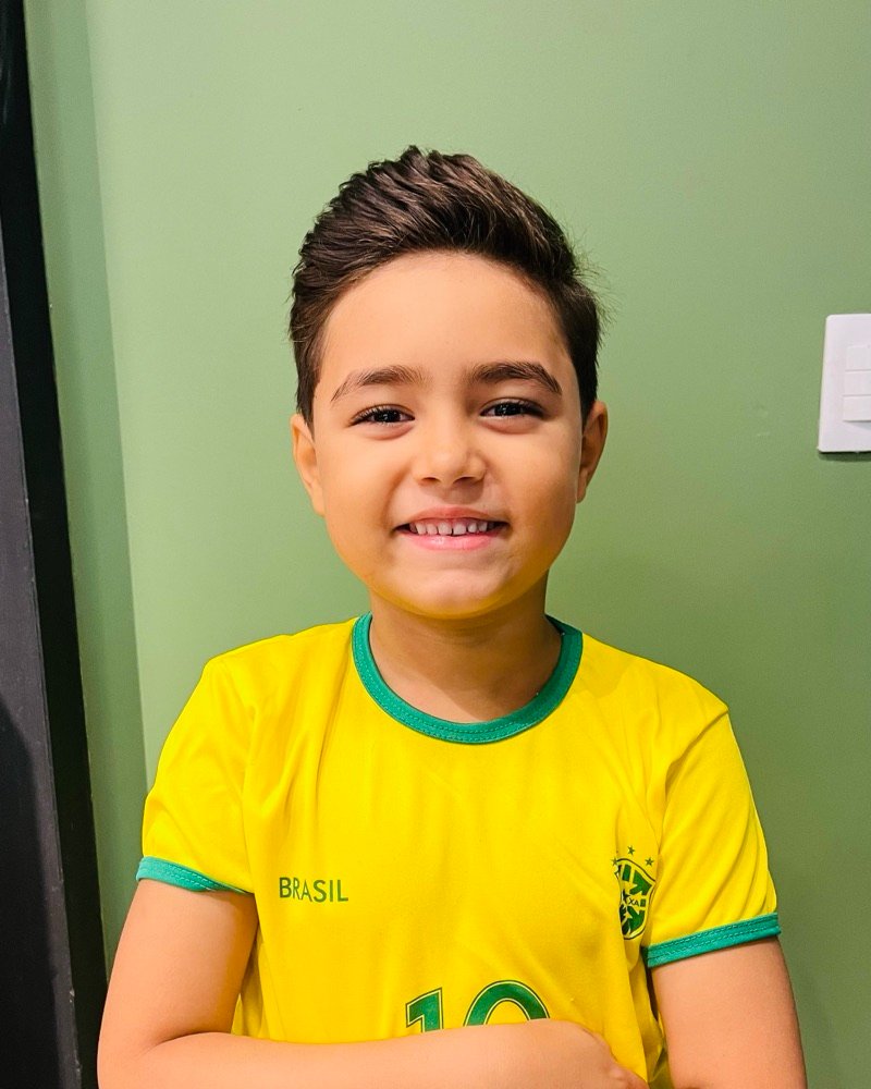 Victor sorrindo, de braços cruzados, com a camisa do Brasil